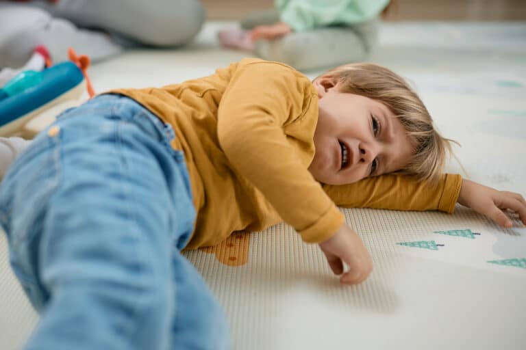 sad little boy crying while lying down on floor.