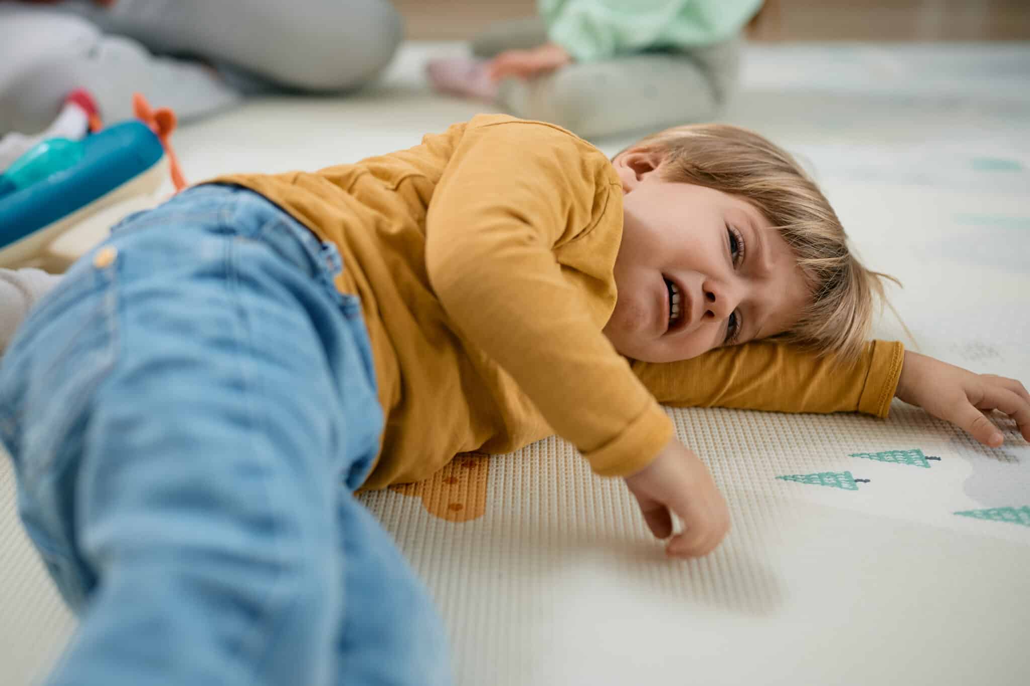 sad little boy crying while lying down on floor.
